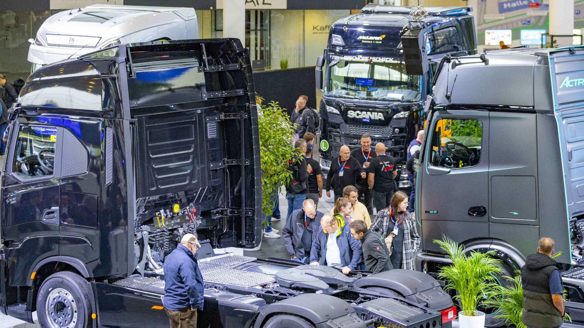 Messebesucher besichtigen moderne LKW-Fahrgestelle und Zugmaschinen in der Ausstellungshalle.