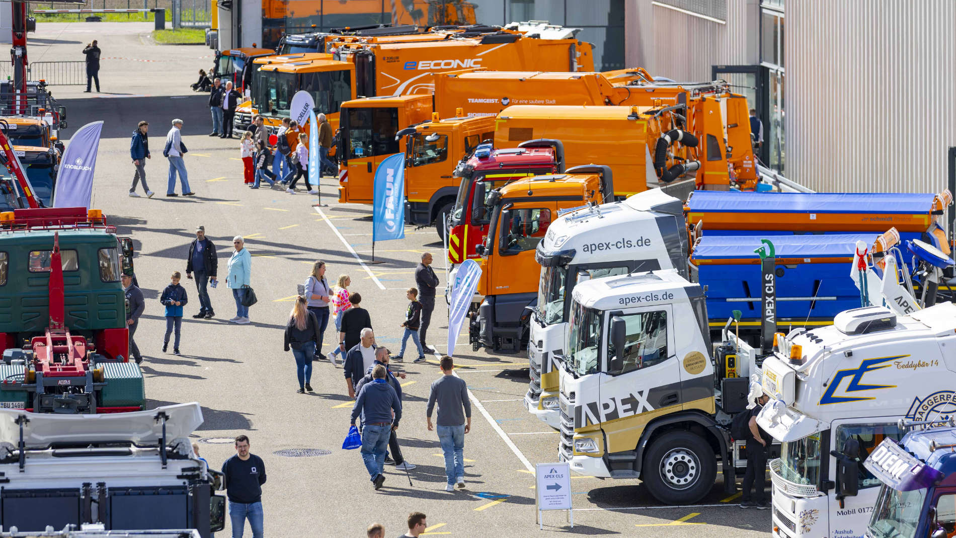 Außenbereich mit zahlreichen LKW und Kommunalfahrzeugen auf der Nutzfahrzeugmesse, Besucher schlendern über das Gelände.