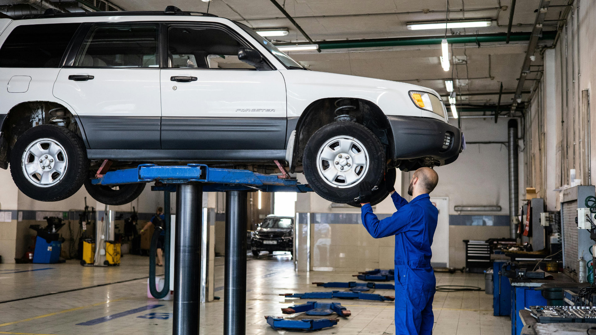 Mechanic examines car on a lifting platform