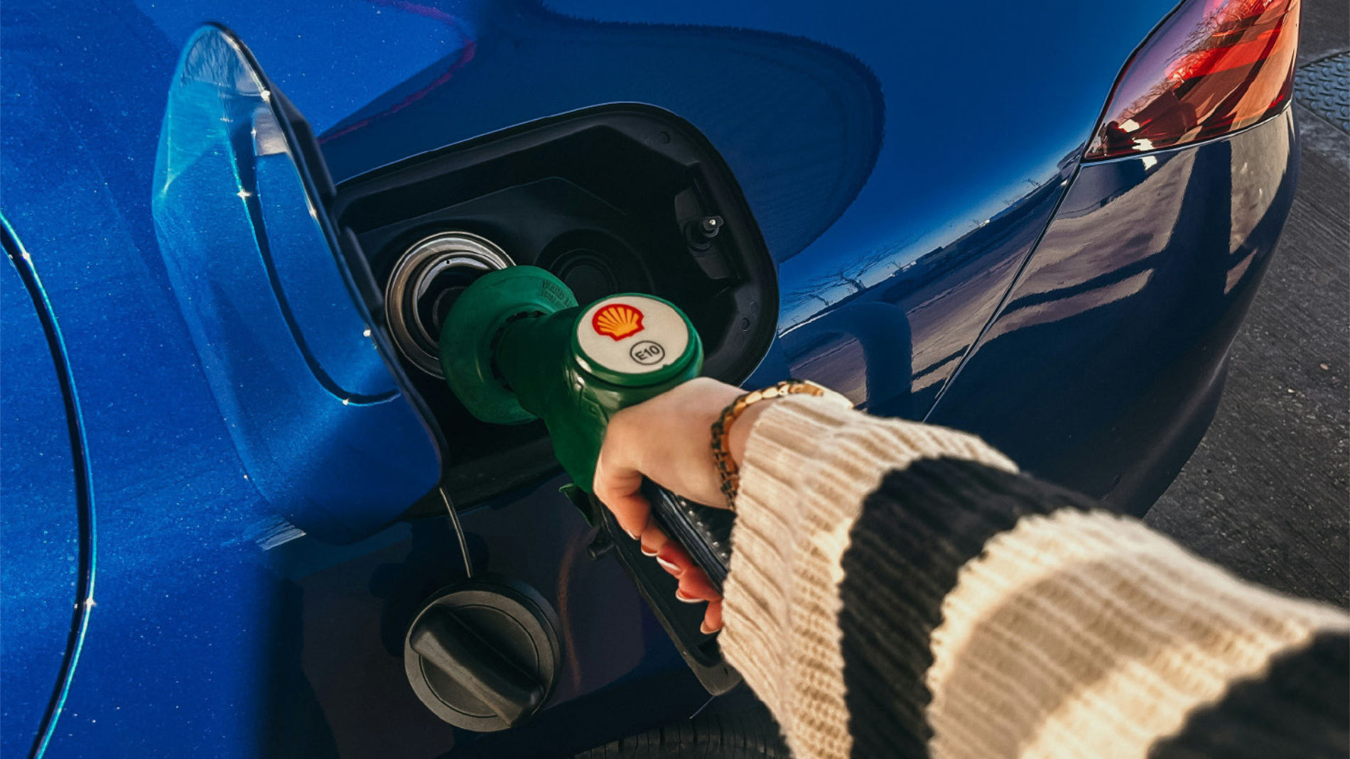 Person, die ein Auto mit einer Zapfpistole betankt