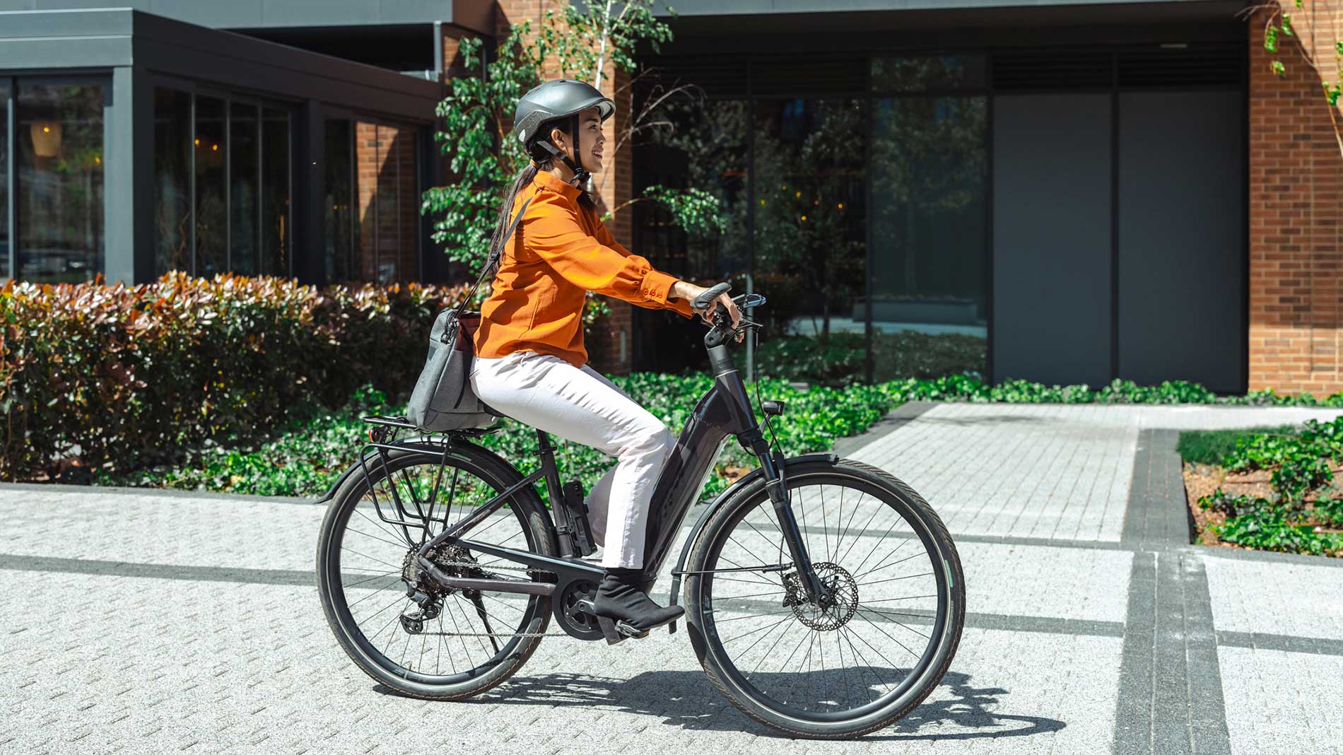 Woman riding an e-bike through a modern residential area