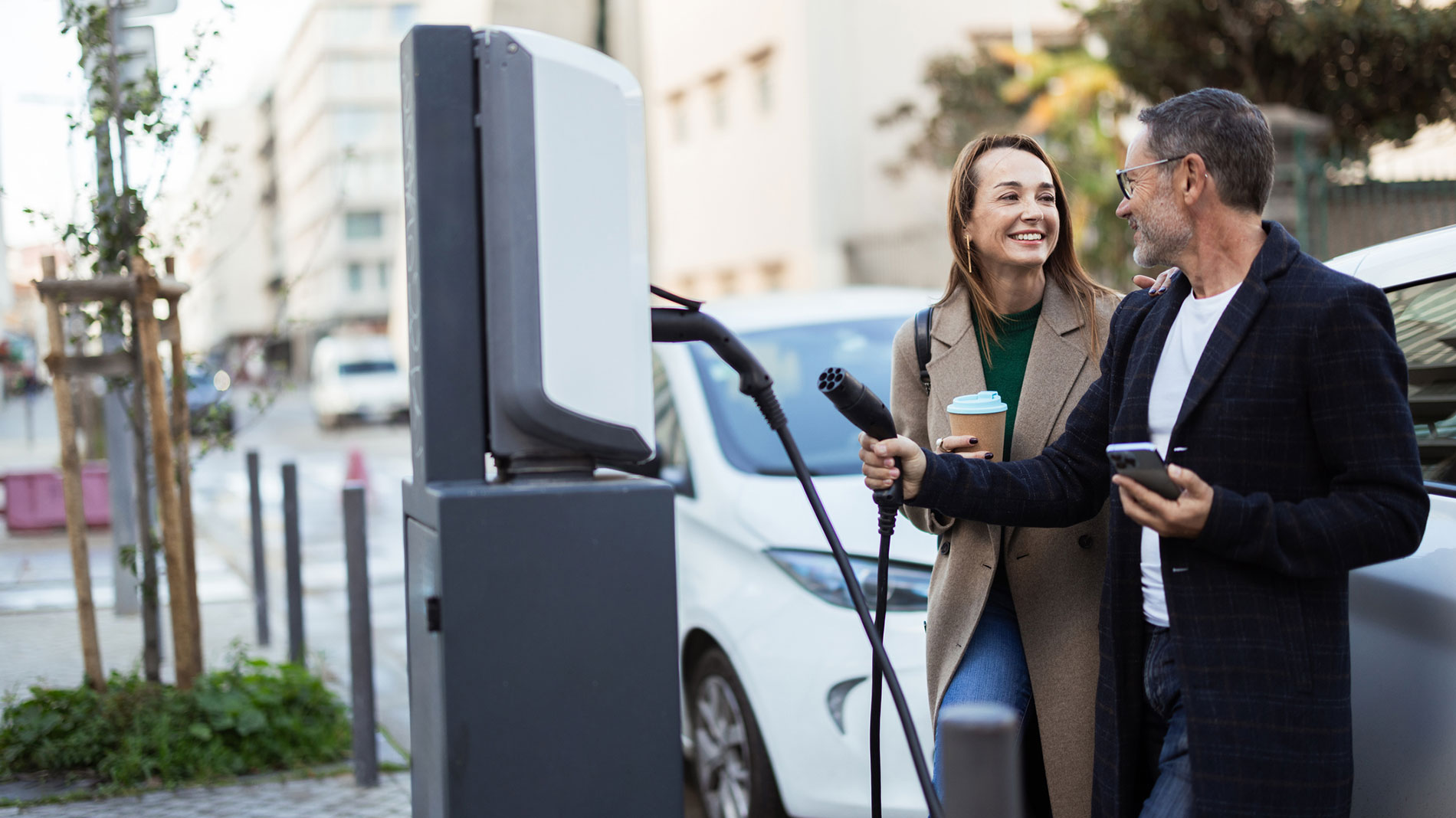 Couple charging an electric car at a public charging station