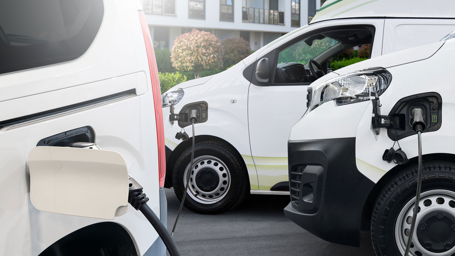 Multiple electric delivery vans charging at stations