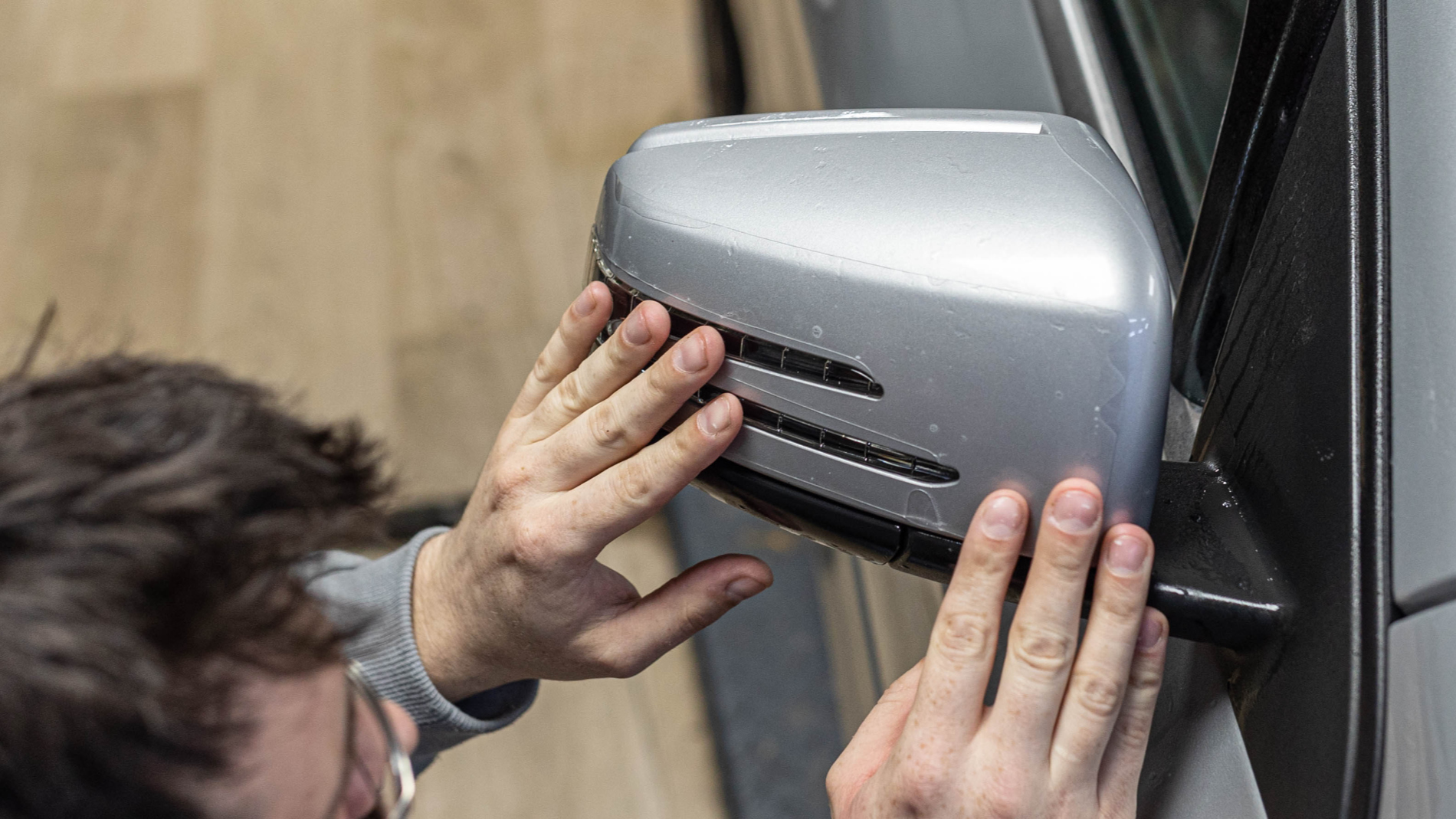 A man checks a wing mirror for paint damage