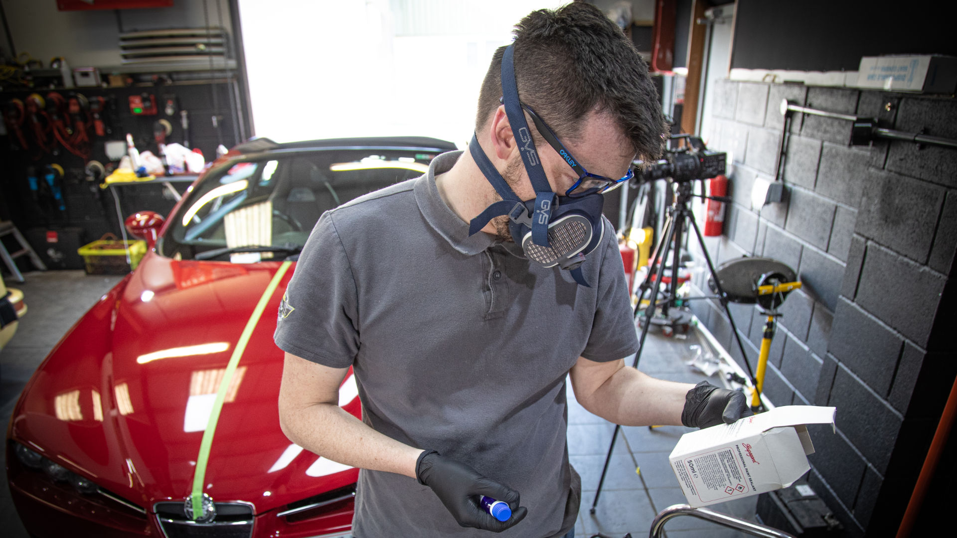 Man in a garage with protective mask and chemicals