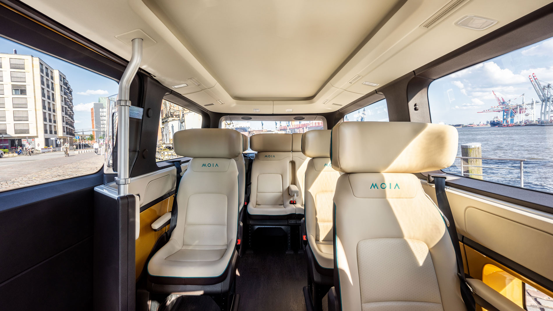 Interior view of a Moia shuttle with modern seats and view of Hamburg harbour