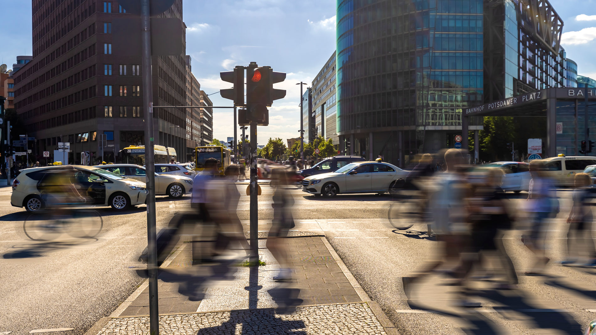 Traffic and pedestrians at busy intersection in modern city centre on sunny day