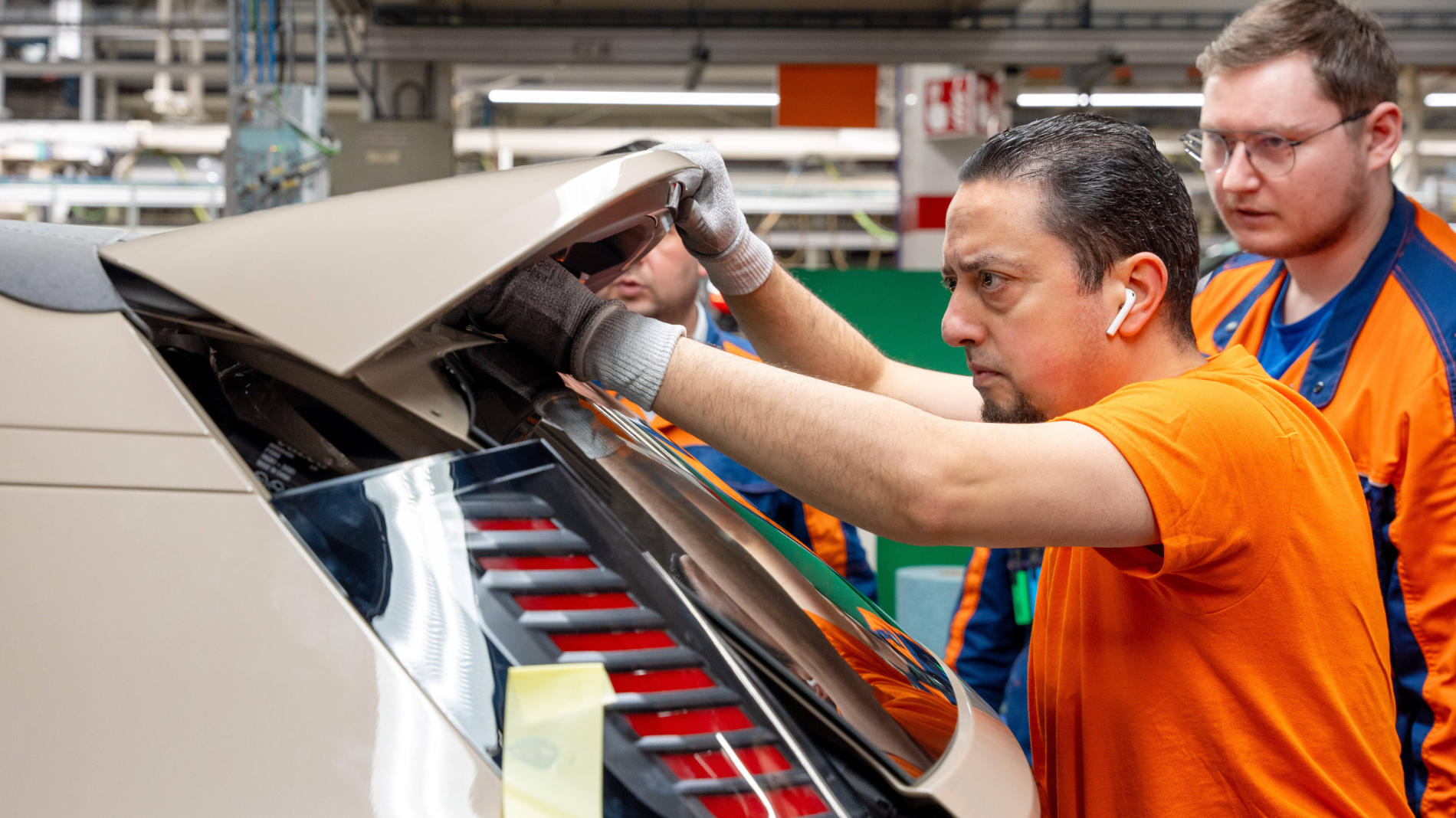 Employees carefully inspecting a car’s tailgate during final assembly.
