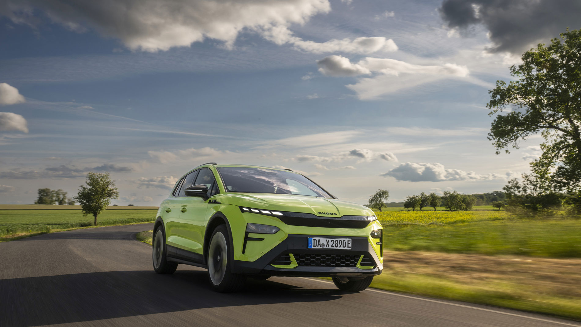 A green Škoda Elroq is driving along a country road