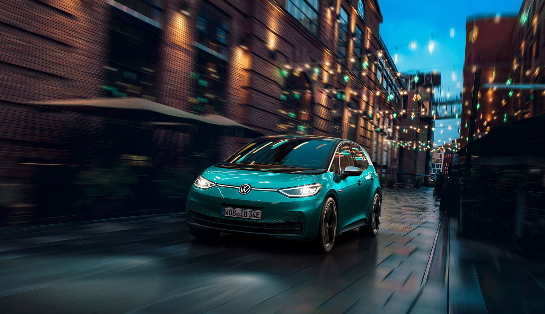 A turquoise VW ID.3 drives through a city at night