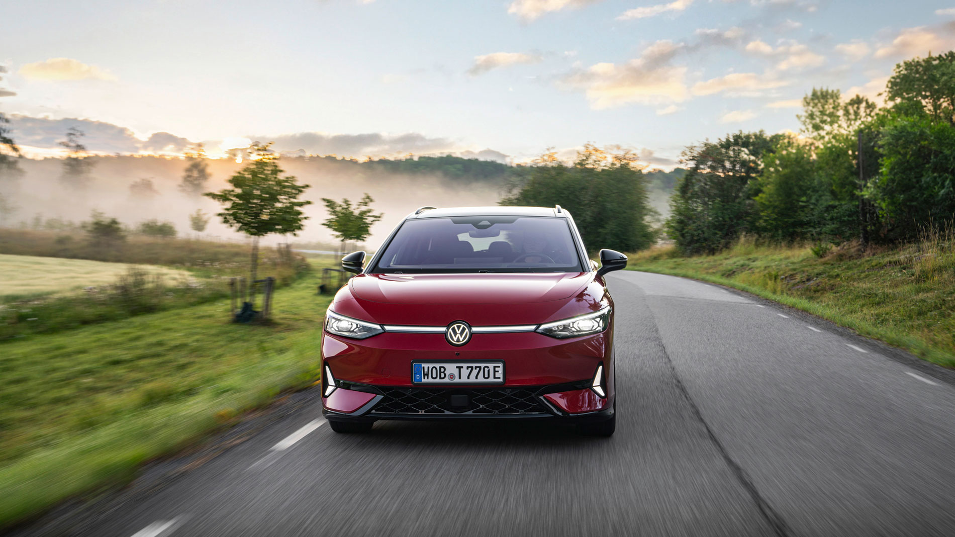 A red VW ID.7 is driving along a country road