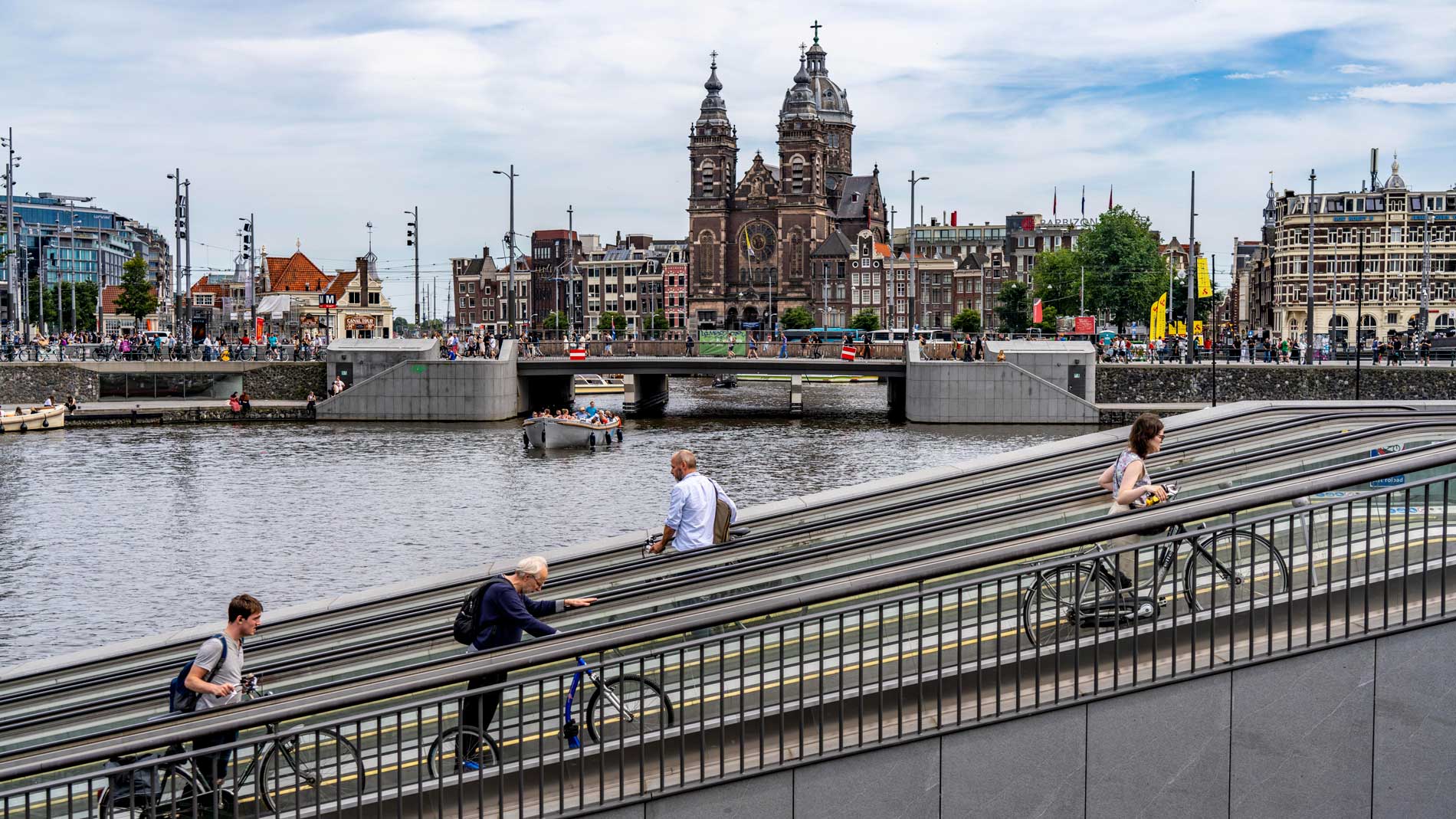 Menschen schieben Fahrräder über Brücke am Kanal