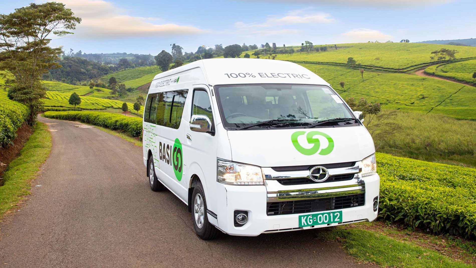 Electric minibus on rural road through green tea landscape in East Africa