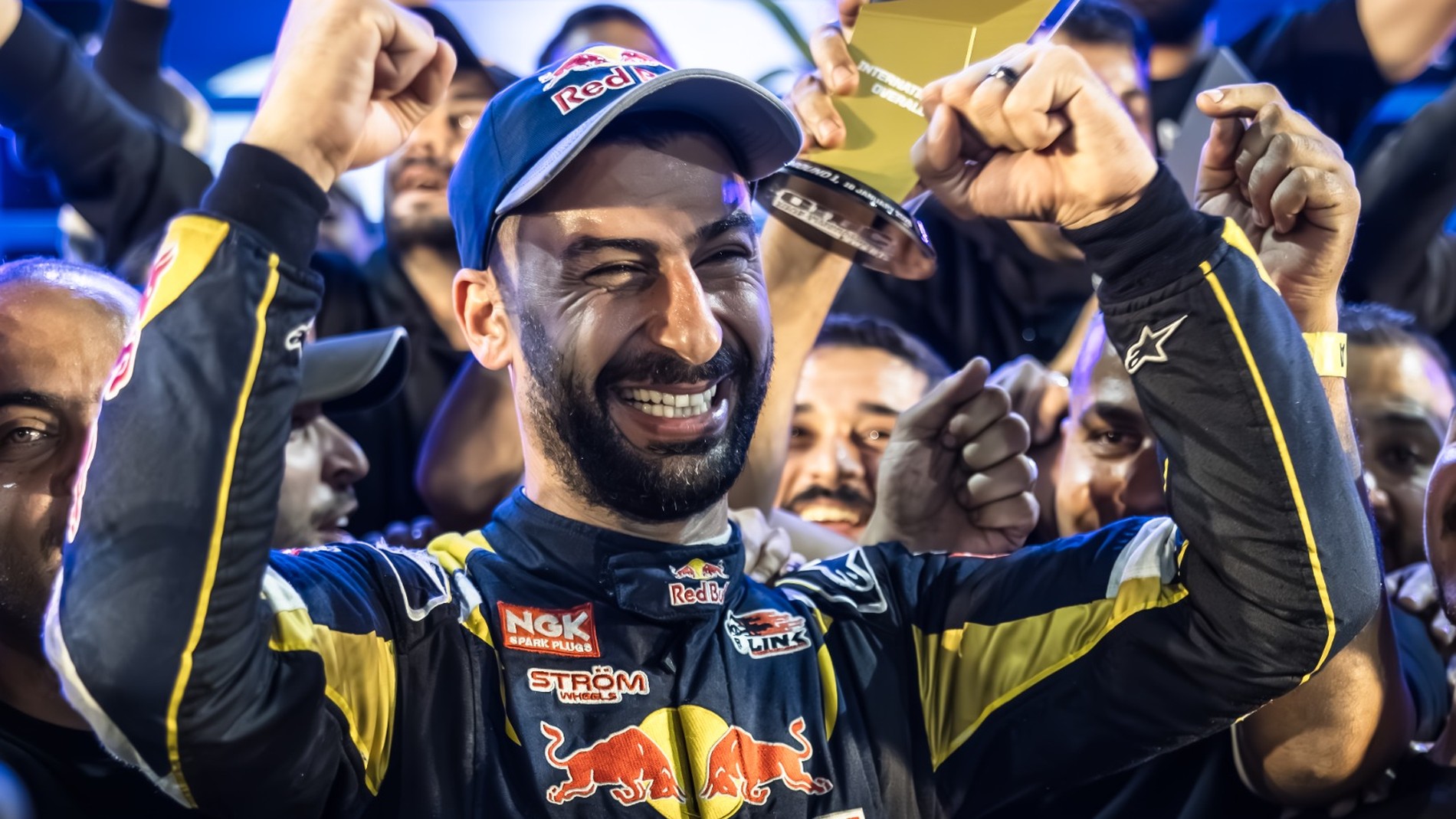 Rennfahrer feiert Sieg mit Team und Pokal